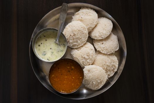 a top view of south karnataka homemade rave idly, sambar & chutney isolated on wooden table