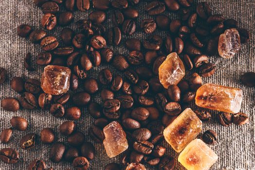 Roasted coffee beans and crystalline sugar scattered on cloth