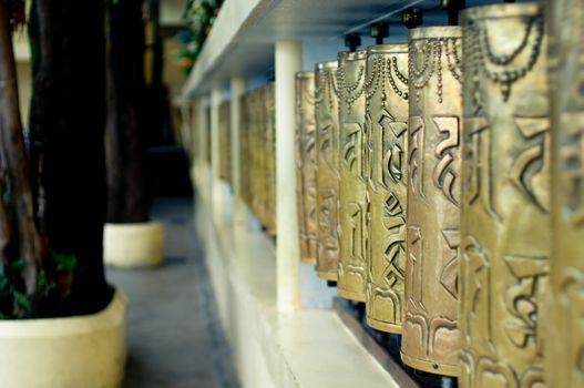 Religious copper buddhist prayer wheels with a prayer mantra written on it in a pilgamage spot in a monastary. Shot in mcleodganj, nepal,kathmandu