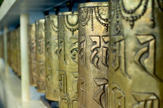 Religious copper buddhist prayer wheels with a prayer mantra written on it in a pilgamage spot in a monastary. Shot in mcleodganj, nepal,kathmandu