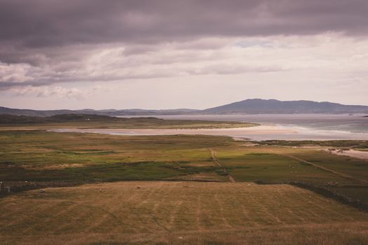 Landscape photo looking out over Irish farmland in County Mayo with mountains and the sea in the background.