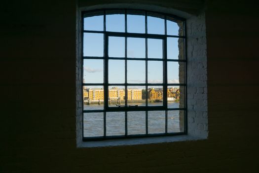 View through old multipane window to buildings on other side River Thames through old wharf building windows. Wapping, London buildings Metropolitan Wharf.