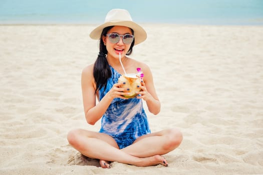 Happy woman with fresh coconut water on the beach