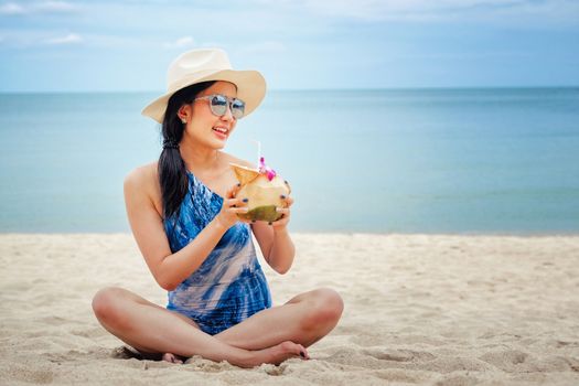 Happy woman with fresh coconut water on the beach