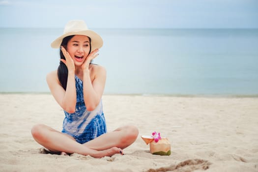 Happy woman with fresh coconut water on the beach