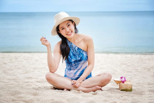 Happy woman with fresh coconut water on the beach