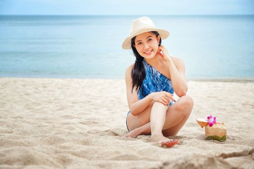 Happy woman with fresh coconut water on the beach