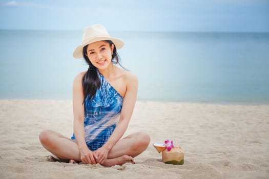 Happy woman with fresh coconut water on the beach