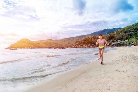 Runner woman running on beach in sunrise