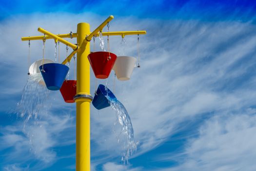 Water spilling out of buckets at a summer splashpad park in the summer sun