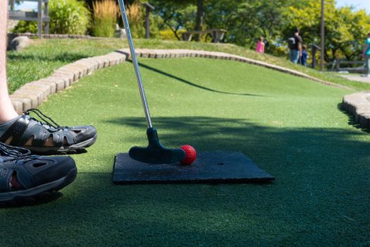 Mini golf course green with a man putting the ball