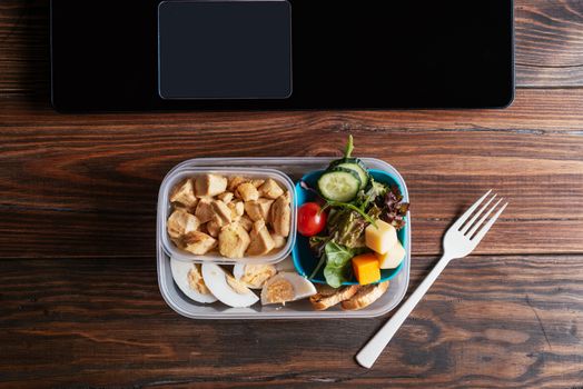 Healthy food in lunch box, on working table with laptop .eating at workplace. Home food for office concept 