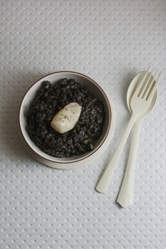 Black rice with cuttlefish, on black cement dish and grunge background