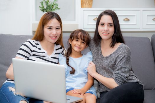 Mother, Aunt and kid having time together lerning with using laptop at home on couch, family concept.