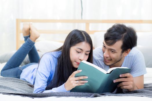 Couple reading a book together in bedroom on the morning with happiness.