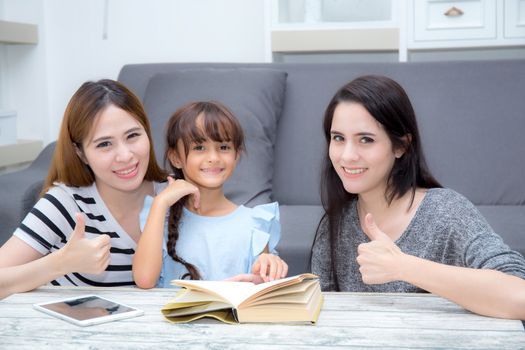 happy family mother, aunt, freind and daughter teaching read a book at home.