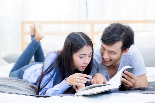 Couple reading a book together in bedroom on the morning with happiness.