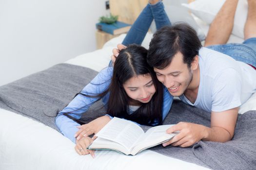 Couple reading a book together in bedroom on the morning with happiness.