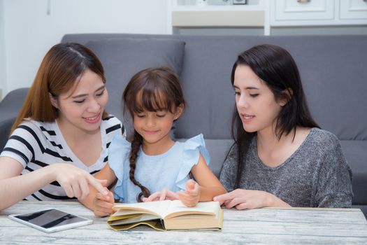 happy family mother, aunt, freind and daughter teaching read a book at home.