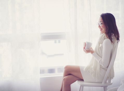 Portrait of bedroom concept: asian woman holding a cup of coffee with on bedroom in breakfast time.
