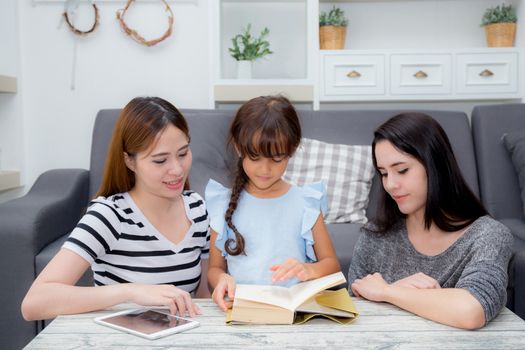 happy family mother, aunt, freind and daughter teaching read a book at home.