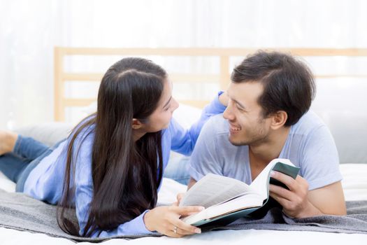 Couple reading a book together in bedroom on the morning with happiness.