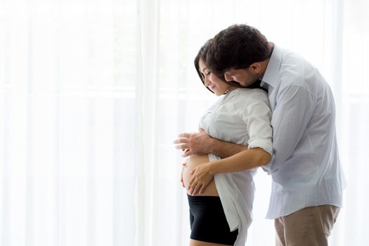 Pregnant Mother and father standing hugging holding belly, family concept.