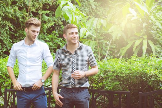 Two friends men talking standing in a garden.