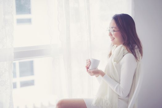 Portrait of bedroom concept: asian woman holding a cup of coffee with on bedroom in breakfast time.