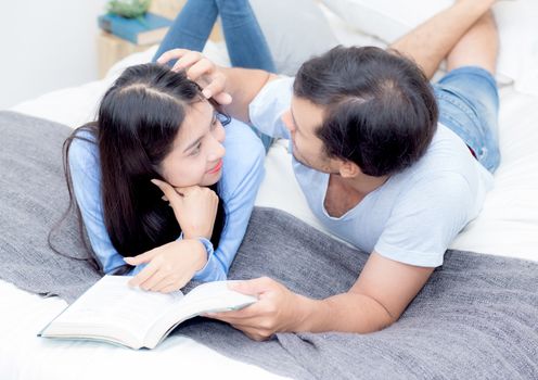 Couple reading a book together in bedroom on the morning with happiness.