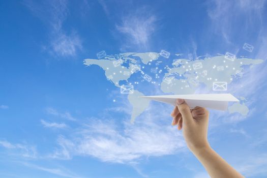 hand with paper plane against blue sky with sending message with email on world map, network communication concept.