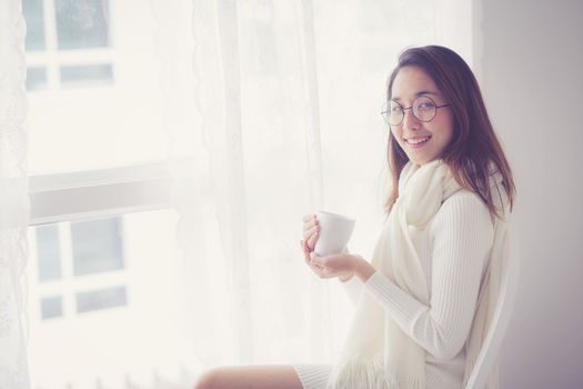 Portrait of bedroom concept: asian woman holding a cup of coffee with on bedroom in breakfast time.