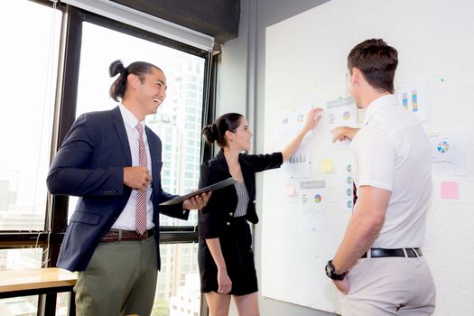 three business people in modern office looking report and analyzing with talking in meeting room.