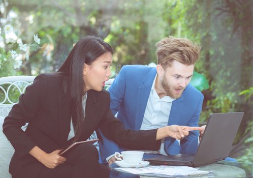 Two business man and woman with laptop - tablet pc computer and papers having discussion in office.