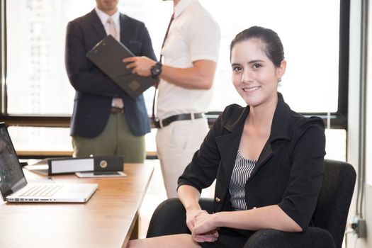 American business woman sitting with people in at modern meeting room.