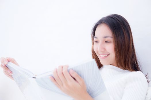 Asian woman reading a book and smiling in bedroom. lifestyle concept.