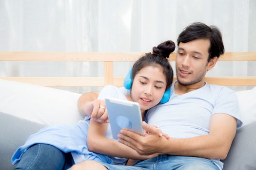 Beautiful asian young couple listening to music with tablet on bed, Love, dating,Young couple in sitting together in bed using a Tablet.