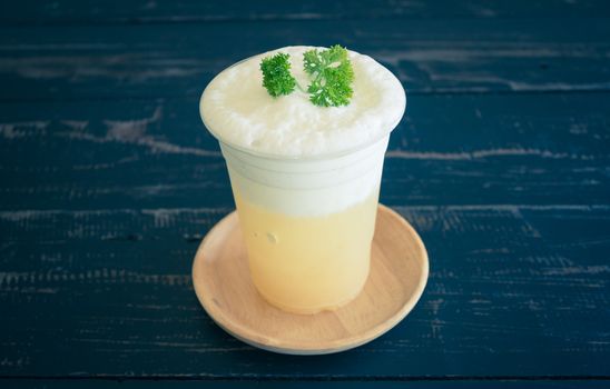 Pineapple juice with Milk froth and Parsley on Black Wood Table. Pineapple juice beverage in plastic glass on wood table. Pineapple juice beverage for food and drink category