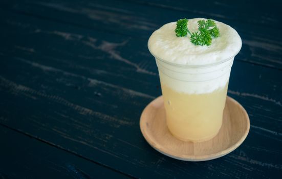 Pineapple juice with Milk froth and Parsley on Black Wood Table. Pineapple juice beverage in plastic glass on wood table. Pineapple juice beverage for food and drink category