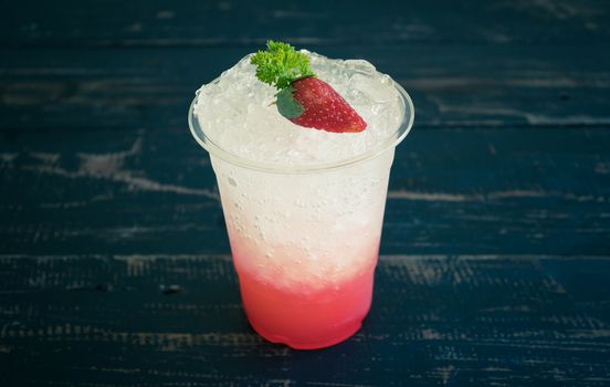 Red Italian Soda Cold Beverage and Strawberry Fruit and Parsley. Red Italian Soda Cold Beverage with strawberry fruit and ice in glass on wood table for food and drink category