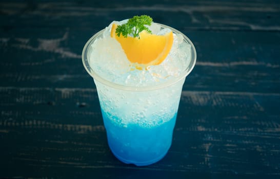Blue Italian Soda Cold Beverage and Lemon Fruit and Parsley. Blue Italian Soda Cold Beverage with Lemon fruit and ice in glass on wood table for food and drink category