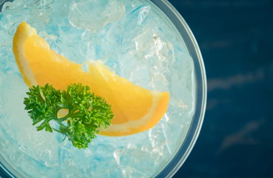 Blue Italian Soda Cold Beverage and Lemon Fruit and Parsley. Blue Italian Soda Cold Beverage with Lemon fruit and ice in glass on wood table for food and drink category