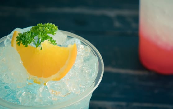 Blue Italian Soda Cold Beverage and Lemon Fruit and Parsley. Blue Italian Soda Cold Beverage with Lemon fruit and ice in glass on wood table for food and drink category