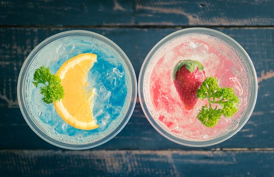 Blue Red Italian Soda Cold Beverage and Lemon Strawberry Fruit and Parsley. Blue Red Italian Soda Cold Beverage on wood table for food and drink category