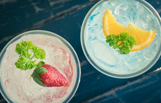 Blue Red Italian Soda Cold Beverage and Lemon Strawberry Fruit and Parsley. Blue Red Italian Soda Cold Beverage on wood table for food and drink category