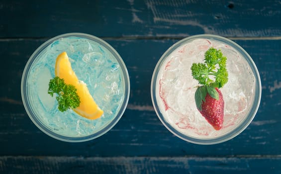 Blue Red Italian Soda Cold Beverage and Lemon Strawberry Fruit and Parsley. Blue Red Italian Soda Cold Beverage on wood table for food and drink category