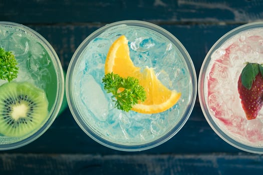 Green Blue Red Italian Soda Cold Beverage and Kiwi Lemon Strawberry Fruit and Parsley. Green Blue Red Italian Soda Cold Beverage on wood table for food and drink category