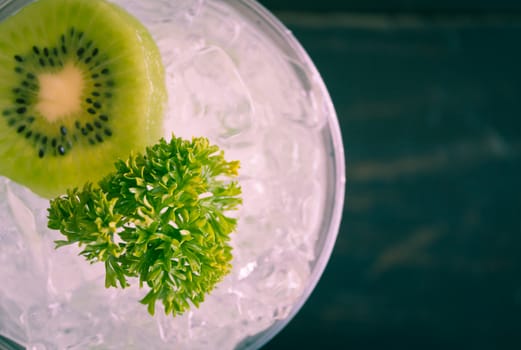 Green Italian Soda Cold Beverage and Kiwi Fruit and Parsley. Green Italian Soda Cold Beverage with Kiwi fruit and ice in glass on wood table. Green Italian Soda with Kiwi for food 
and drink category
