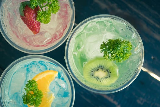 Green Red Blue Italian Soda Cold Beverage and Kiwi Strawberry Lemon Fruit and Parsley. Green Red Blue Italian Soda Cold Beverage on wood table for food and drink category