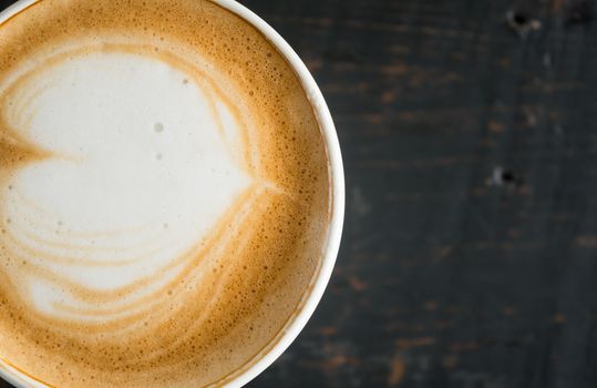 Flatlay Half Heart Shape Froth Milk Latte Art in White Coffee Cup on Black Wood Table. Heart shape froth milk Latte art hot beverage for coffee lover